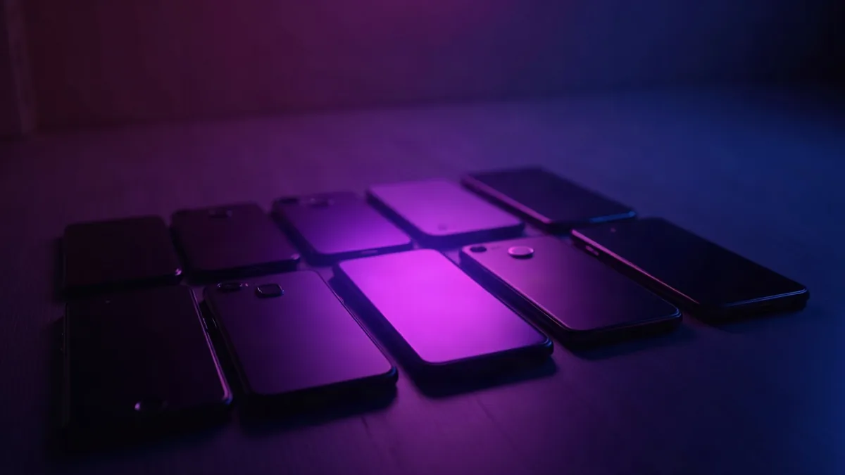 Několik smartphonů v řadě, fialový reflektor míří na ten prostřední (ilustrace k článku)