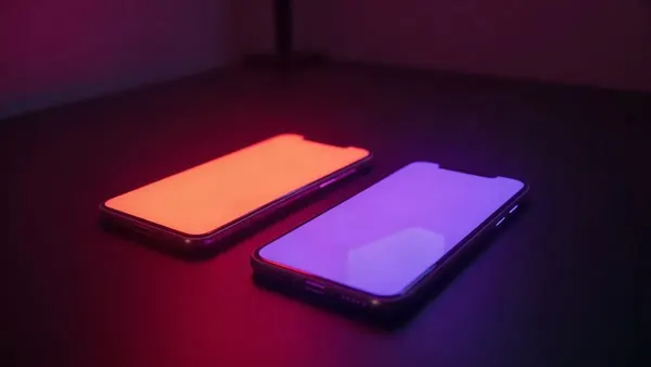 Dva smartphony vedle sebe, jeden oranžový, druhý fialový, neonové odlesky (ilustrace k článku)